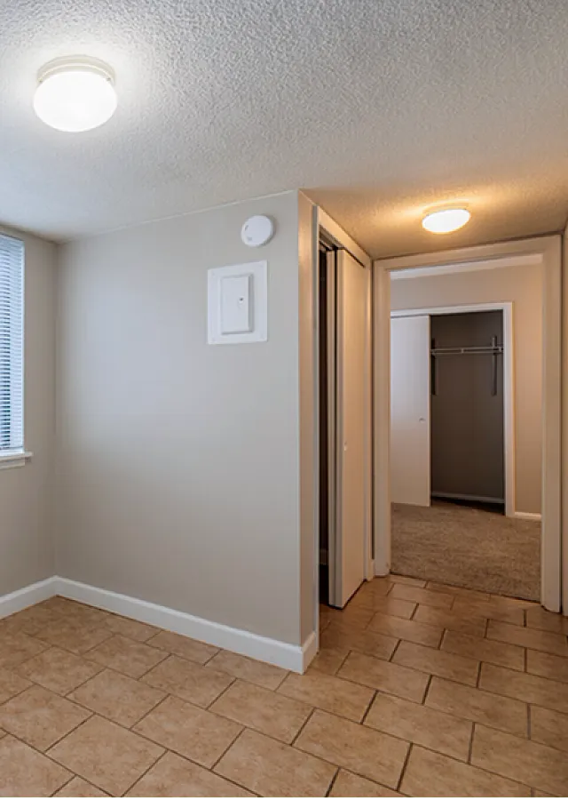 Bright and inviting apartment space with large window, tiled floors, and ample closet storage.