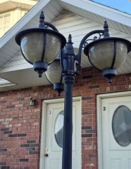 Charming duplex exterior with vintage-style street lamp and classic red brick facade.