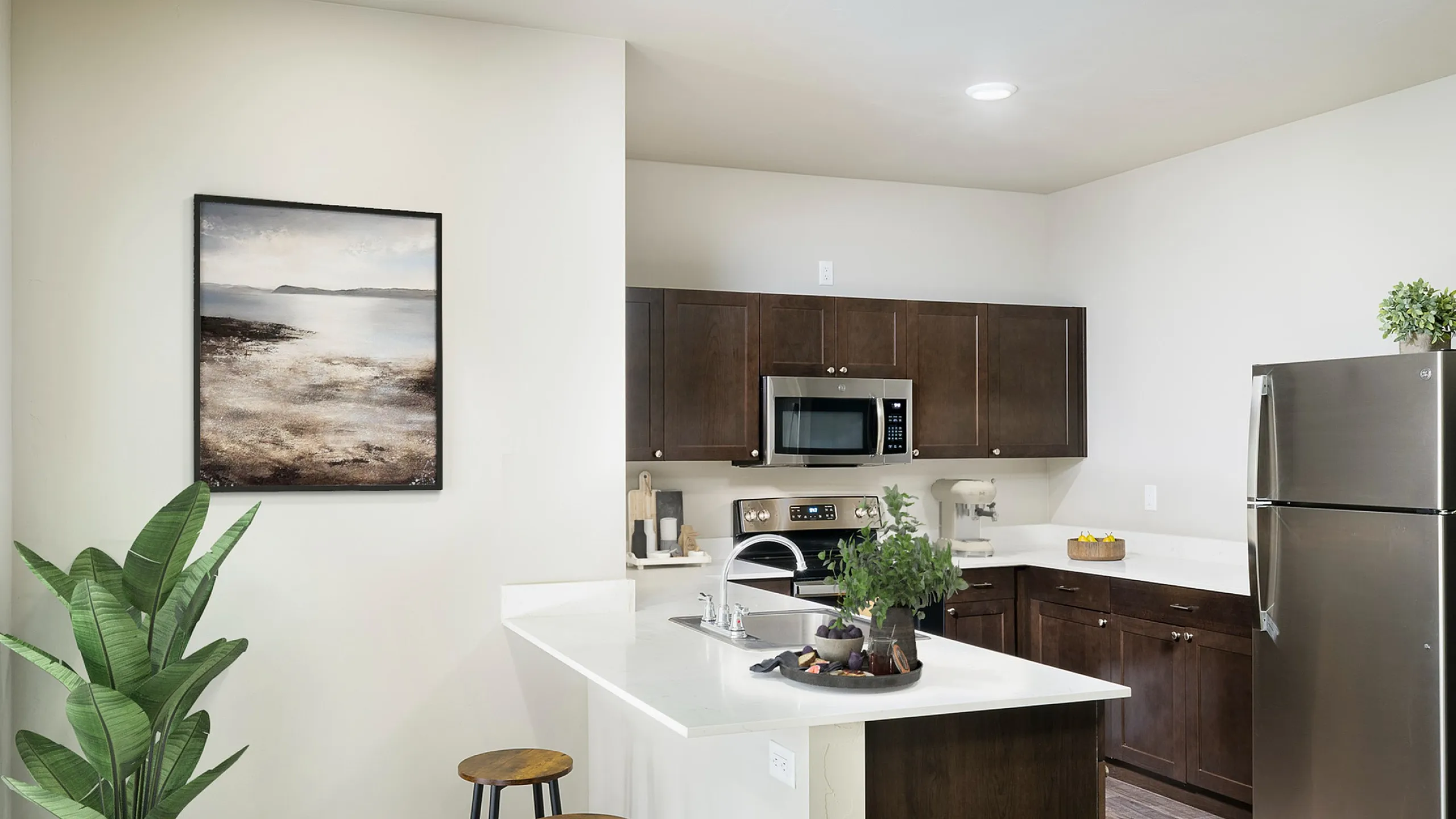 Modern kitchen with sleek stainless steel appliances, wood cabinetry, and a stylish island with bar seating, complemented by elegant flooring and decorative art.