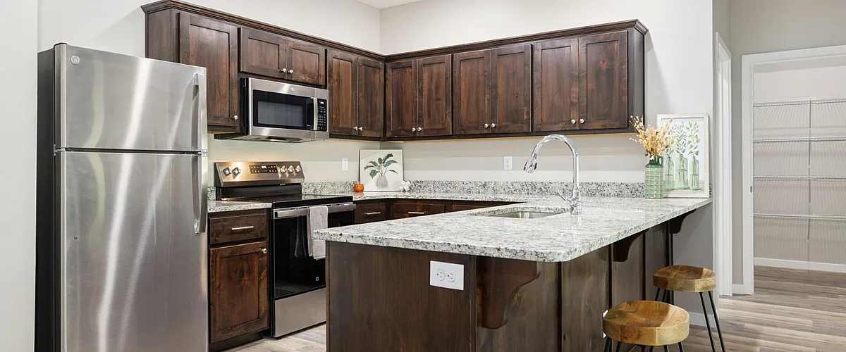 Modern kitchen with sleek stainless steel appliances, rich wood cabinetry, and a spacious granite island with stylish bar stools.