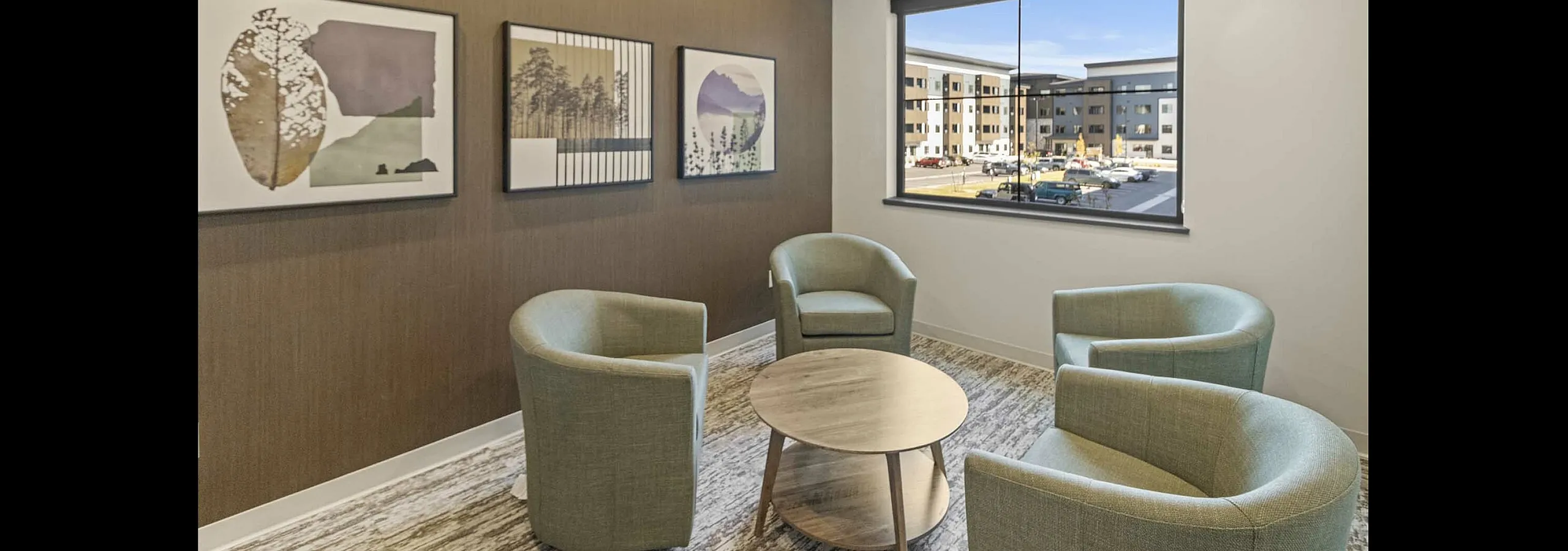 Chic and modern living room with cozy armchairs, stylish wall art, and a large window displaying an urban view.
