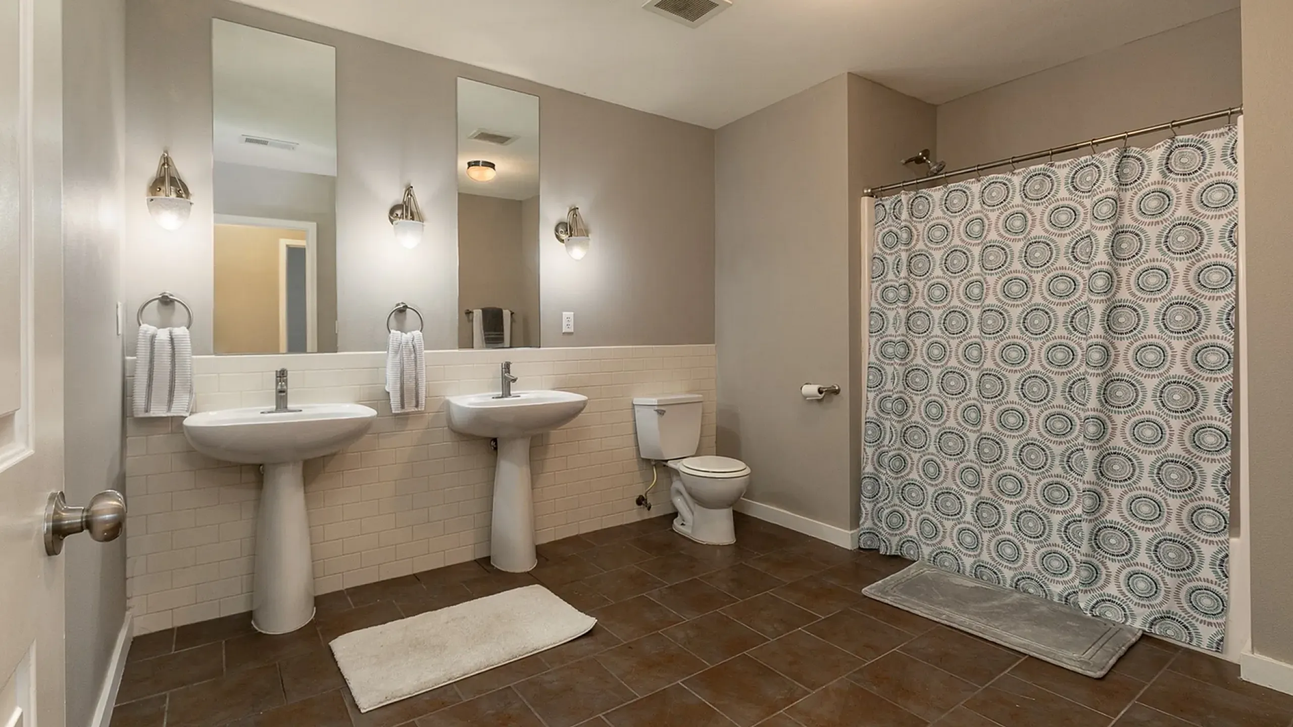 Spacious bathroom featuring dual sinks, elegant lighting, and a stylish shower curtain for modern living.