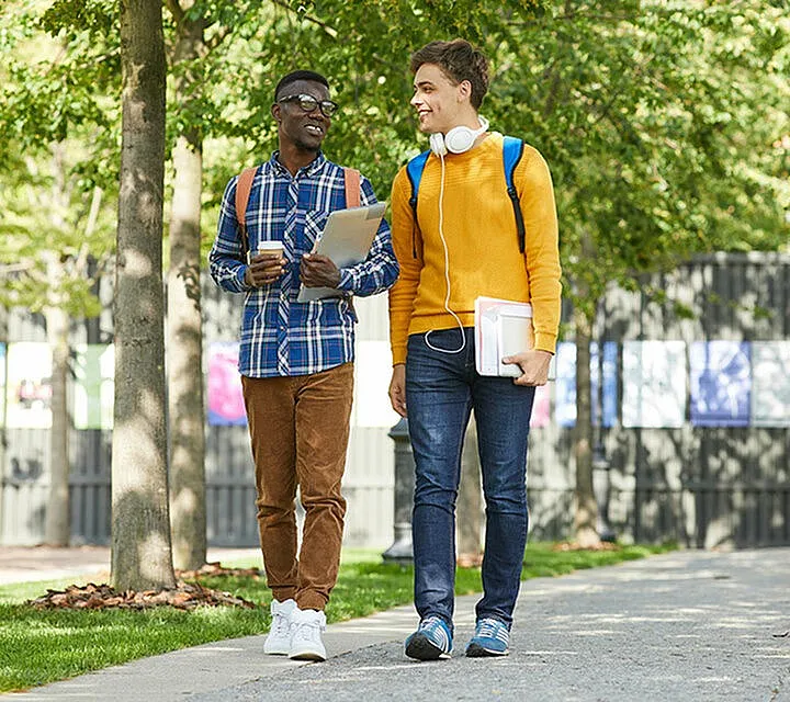 two people walking down a tree lined street