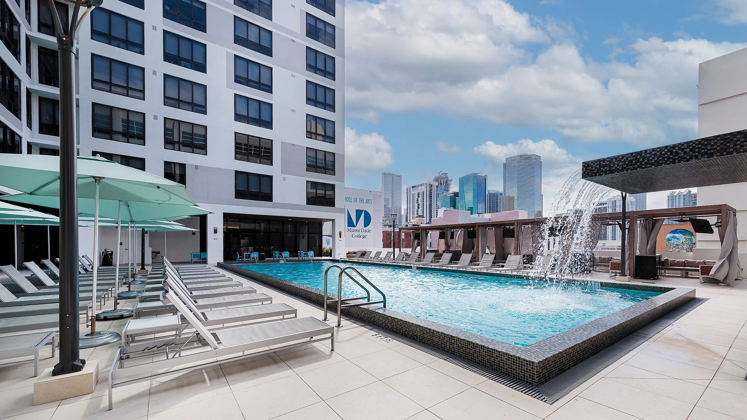 Luxurious rooftop pool area at Grand Station Miami in Downtown Miami with elegant lounge chairs, modern architecture, and city skyline views, perfect for relaxation and entertainment.