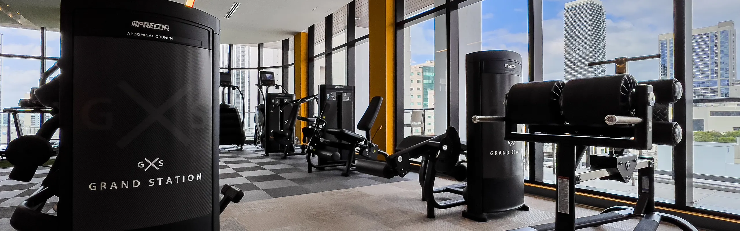 Luxurious gym at Grand Station featuring state-of-the-art equipment with stunning city views through large windows.