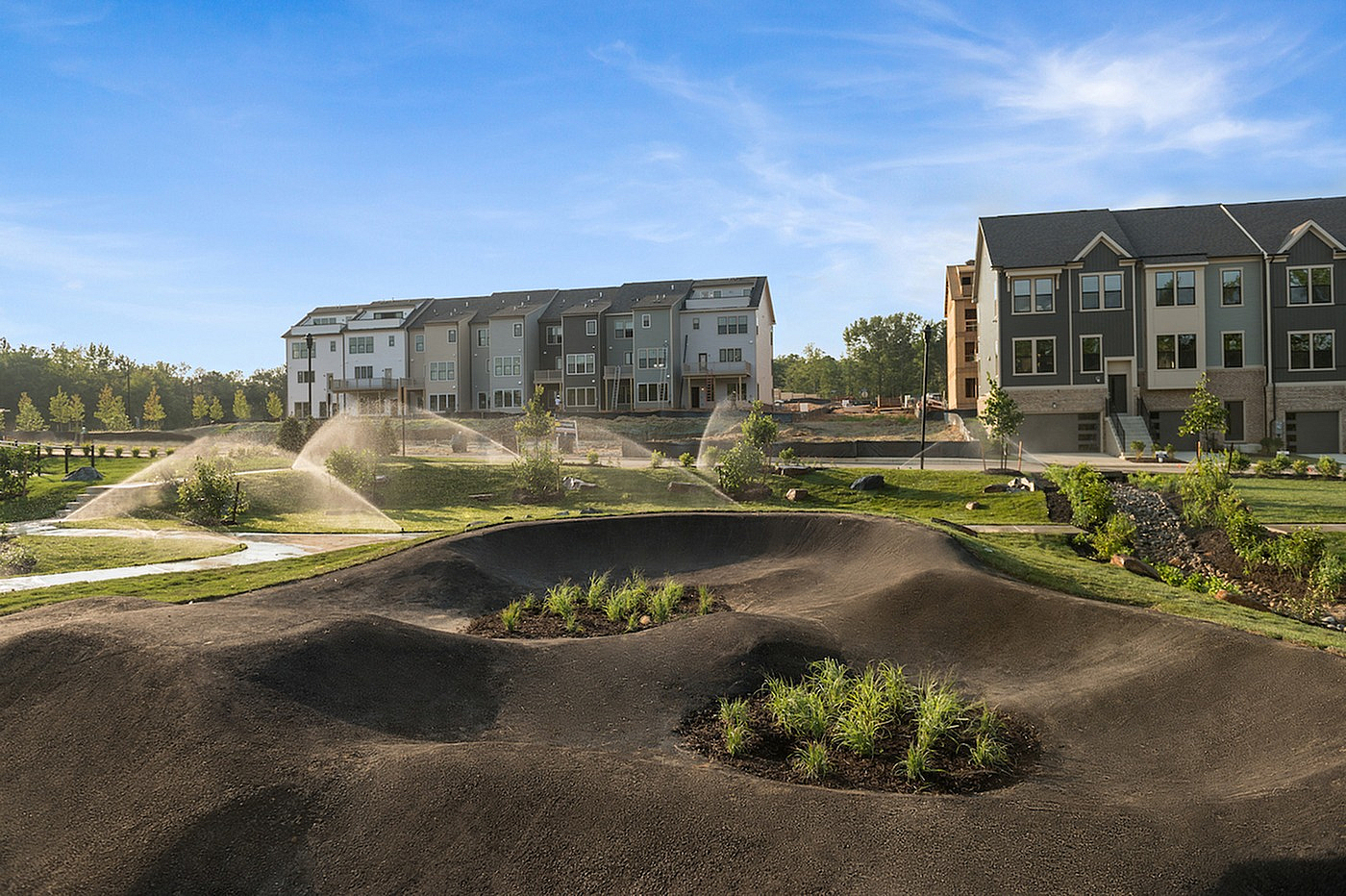 The Current at Watershed courtyard with sprinklers and landscaped mounds - Laurel, MD