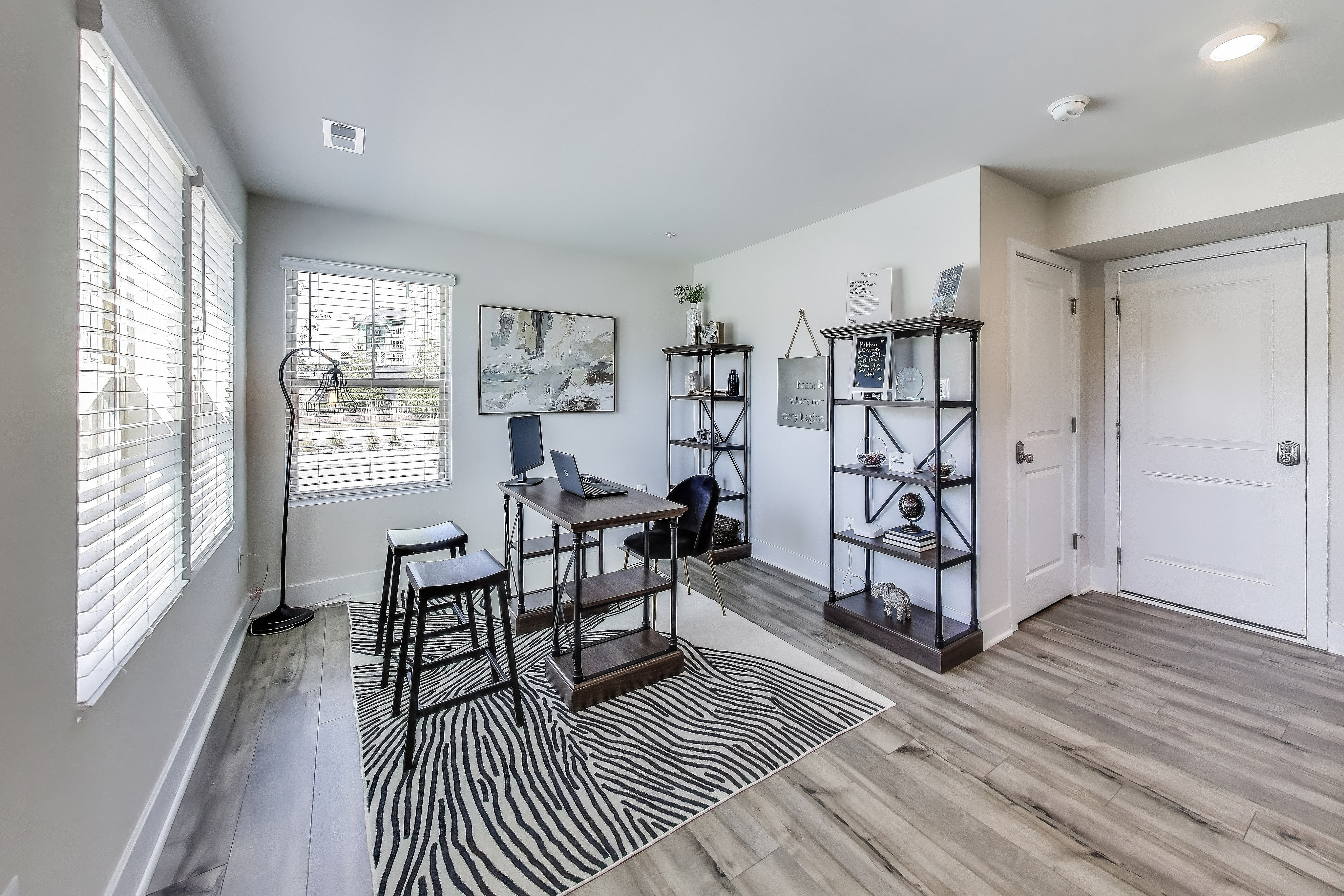 Bright home office with modern decor, featuring large windows, stylish shelves, and chic zebra-patterned rug.
