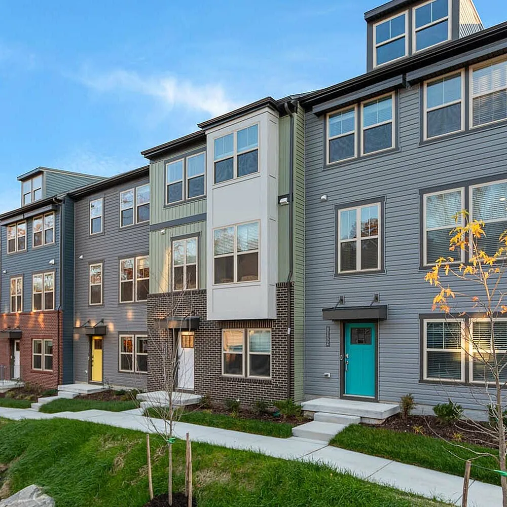Modern townhouse community with colorful facades and welcoming front entrances set against a scenic backdrop.