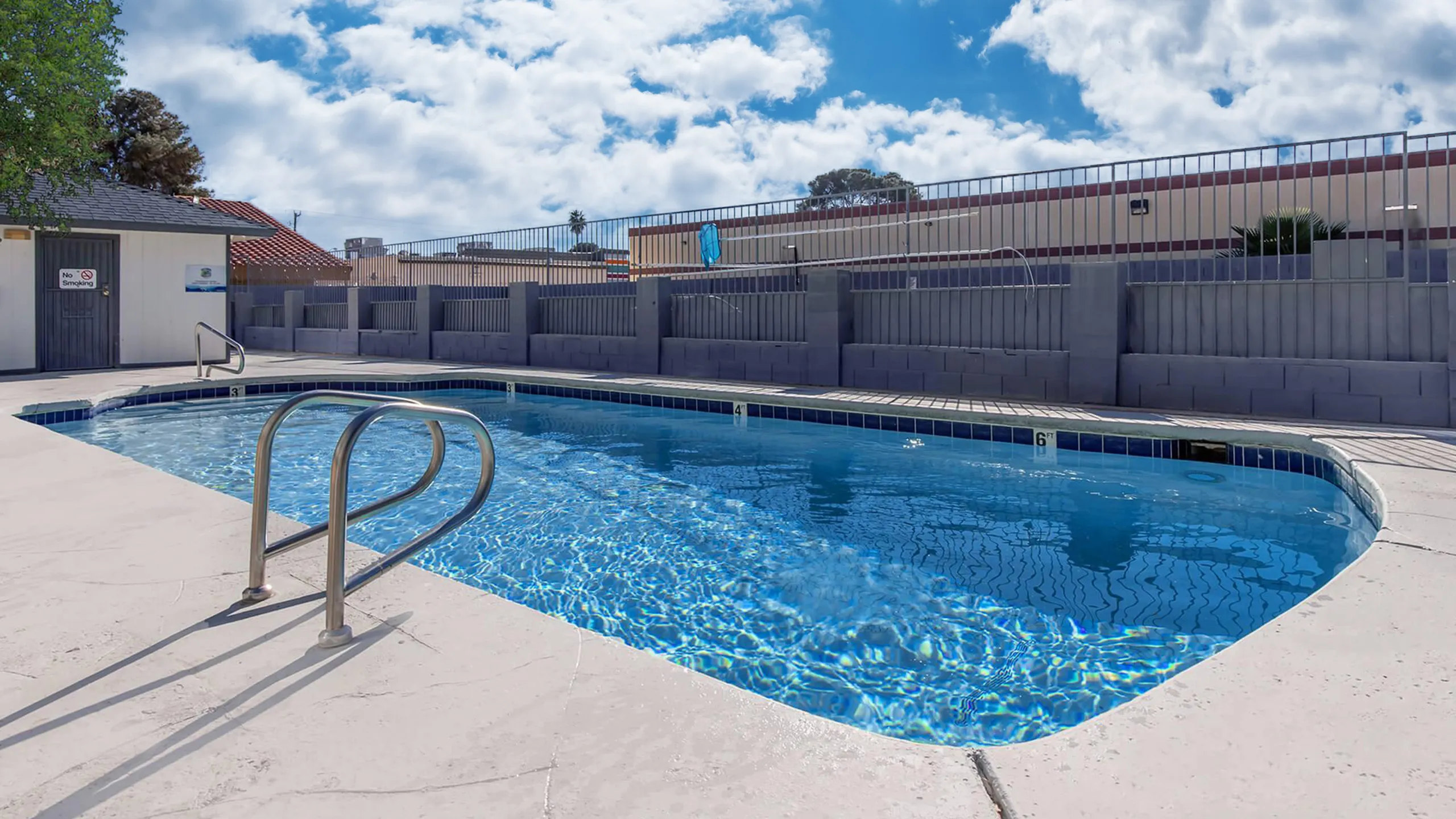 Sunny outdoor pool with sparkling blue water and surrounding deck.