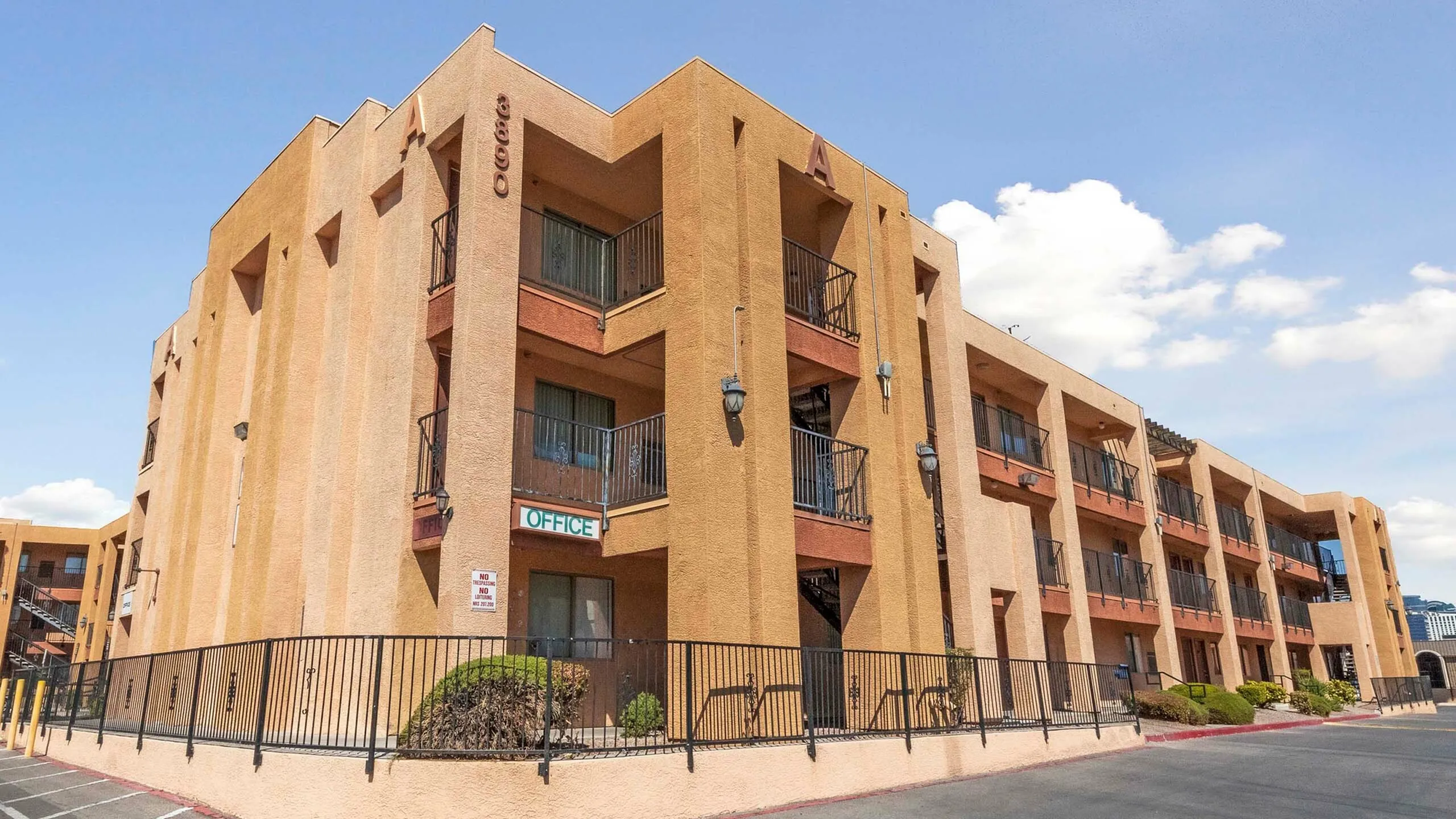 Modern three-story apartment building with a stucco exterior and private balconies.