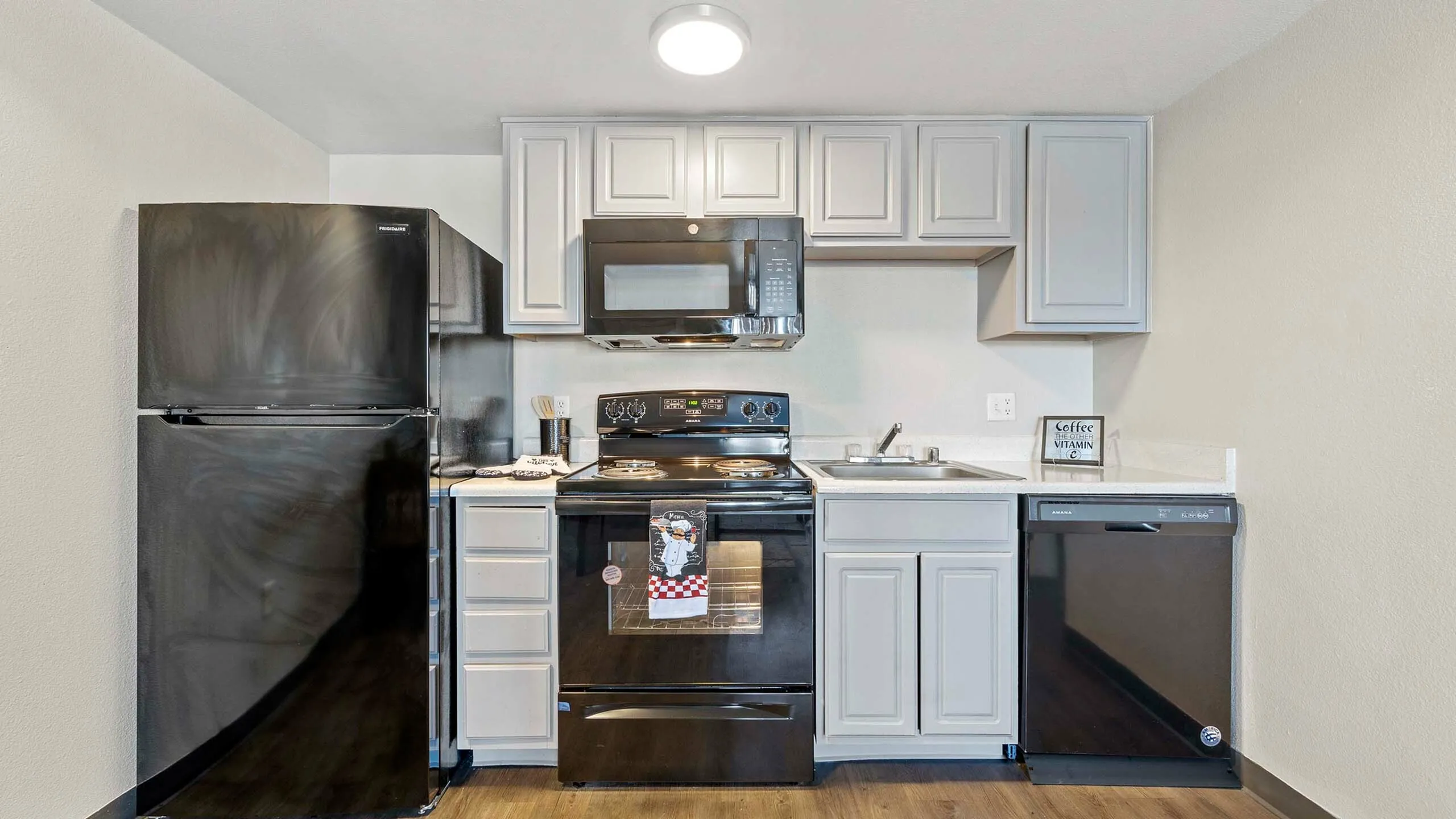 Modern kitchen with sleek black appliances, light cabinetry, and elegant finishes.
