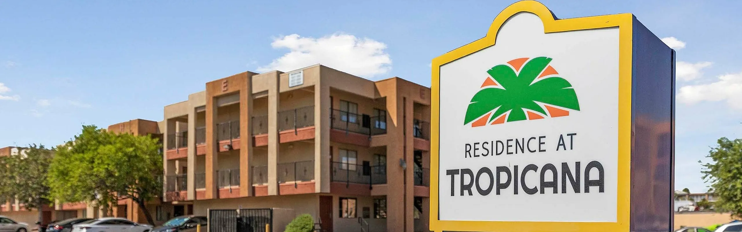 Modern apartment complex with lush greenery and ample parking spaces at Residence at Tropicana.