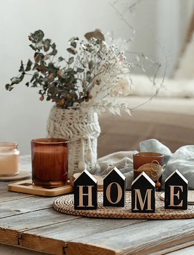 Charming home setting with decorative candles, a woven basket, and block letters spelling 'HOME' on a rustic wooden table.