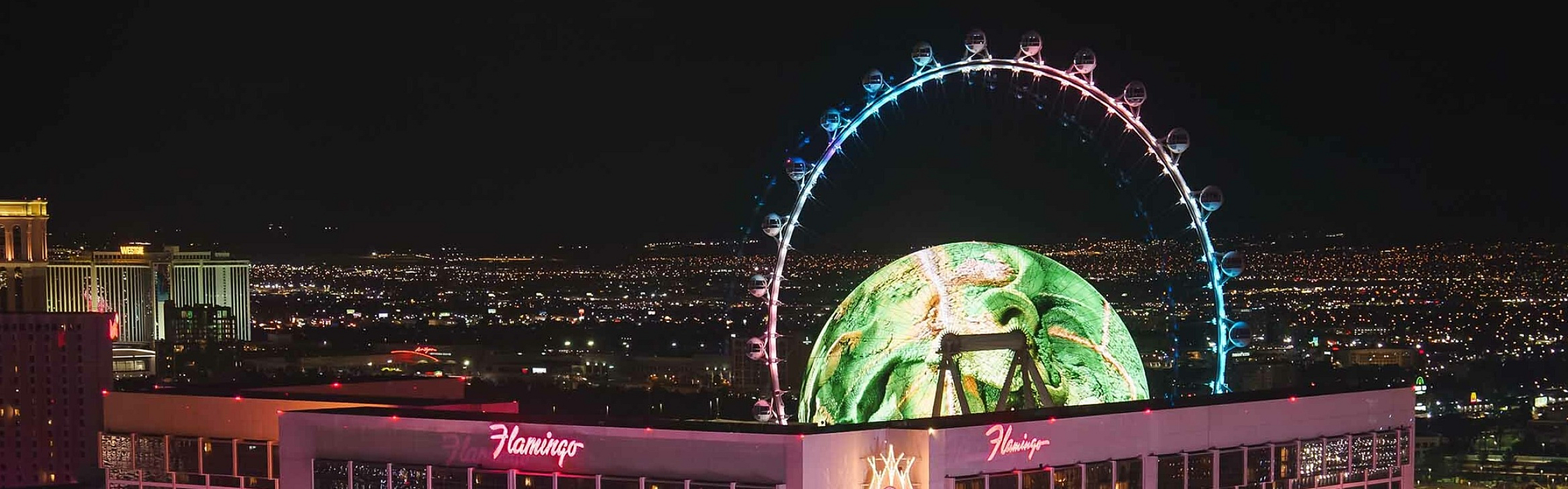 Illuminated cityscape featuring a lively hotel, vibrant lights, and a striking observation wheel.