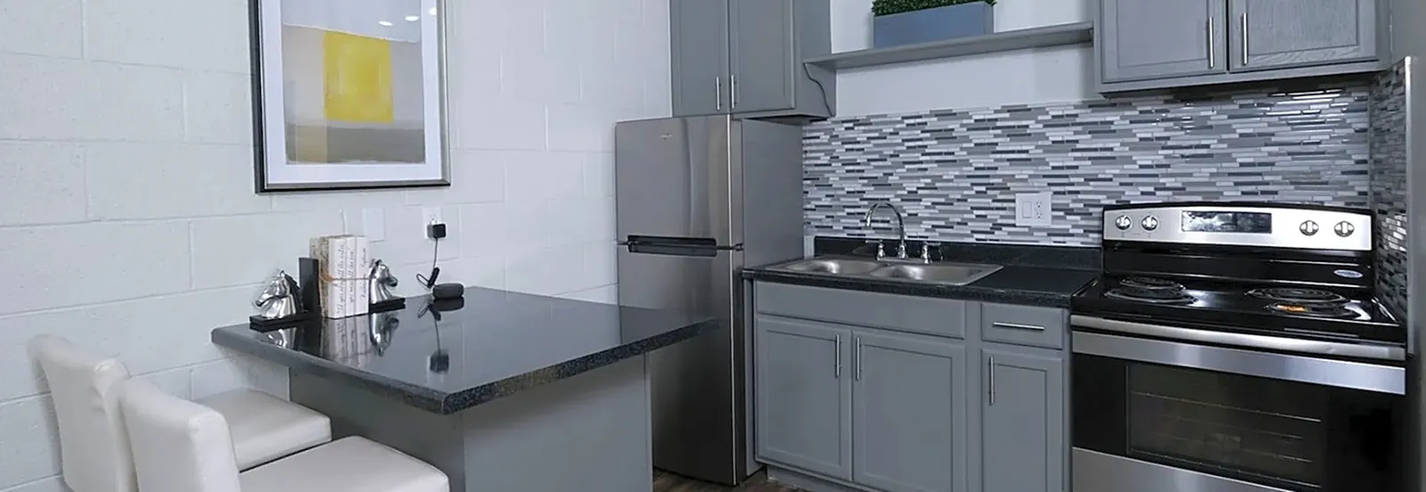 Contemporary kitchen design with sleek gray cabinets, stainless steel appliances, and a patterned backsplash.