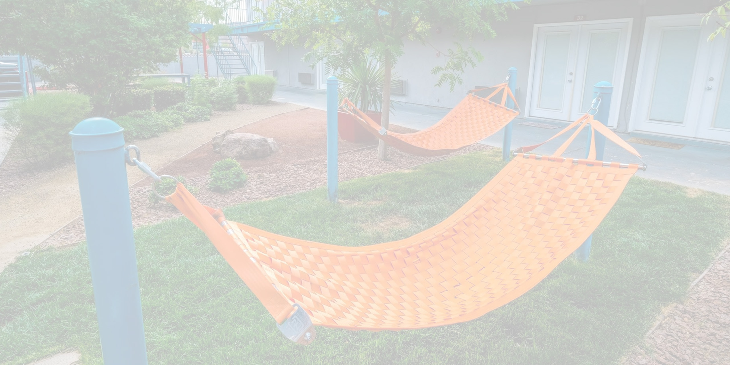 Inviting outdoor area with vibrant orange hammocks under a lush green canopy.