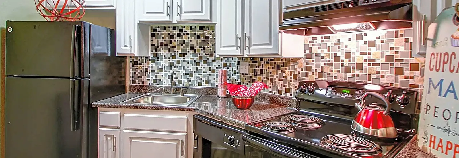 Stylish kitchen with white cabinets, mosaic tile backsplash, and black appliances.