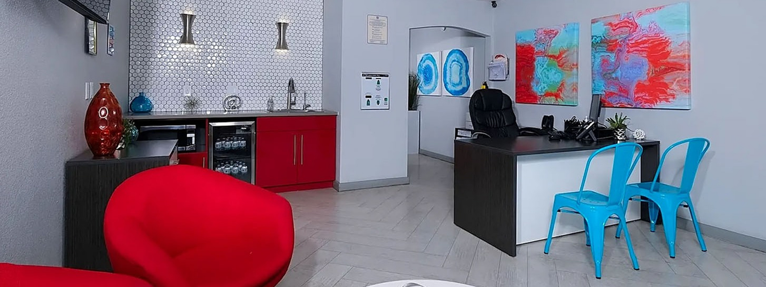 Modern office interior with red and blue accents, featuring a stylish workspace and vibrant artwork.