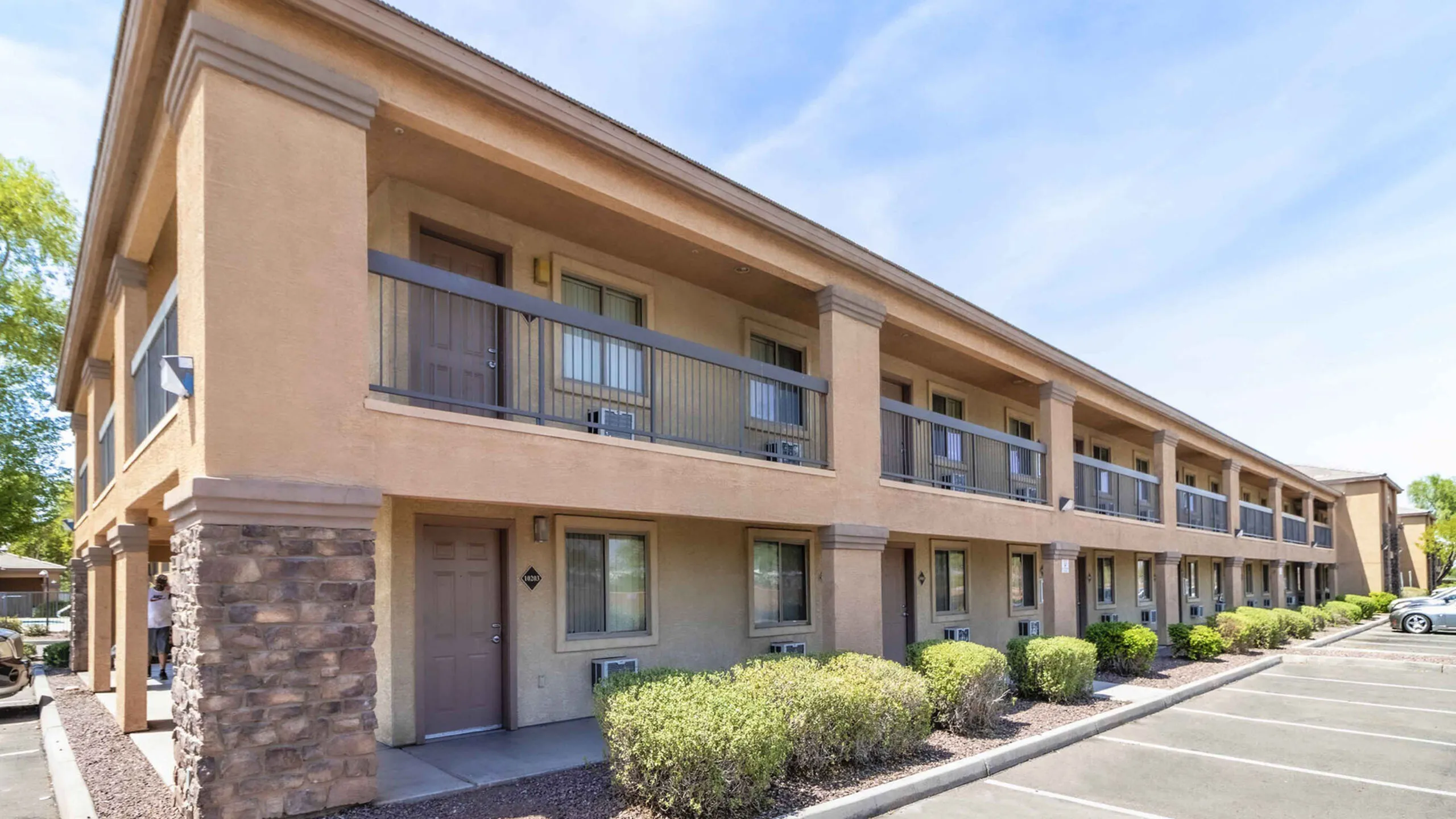 Contemporary two-story apartment building with elegant design, featuring private balconies and lush landscaping.