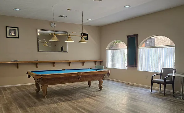 Inviting recreational room with a stylish billiard table, elegant lighting, and large windows for natural light.