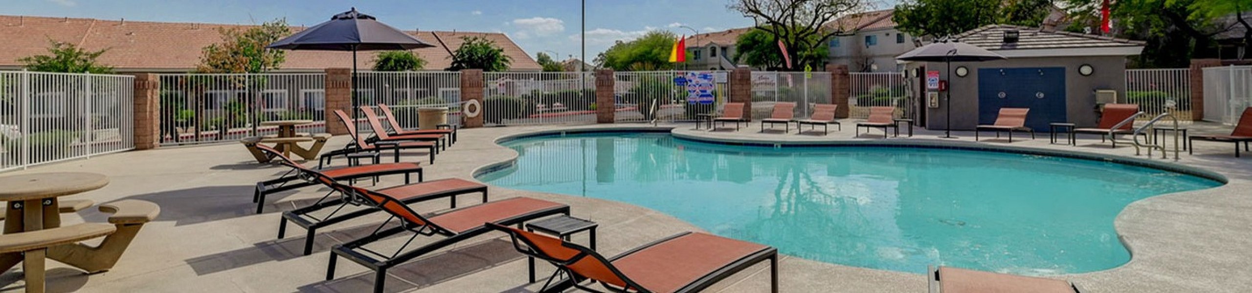 Inviting outdoor pool area with comfortable lounge chairs and a sunshade, perfect for relaxation on a beautiful sunny day.