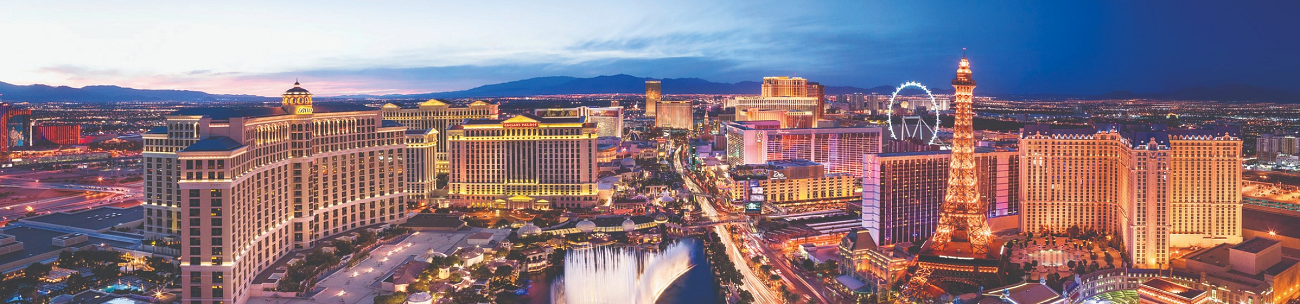 Vibrant aerial view of the Las Vegas Strip at dusk, featuring iconic casinos and hotels lit up with colorful lights.