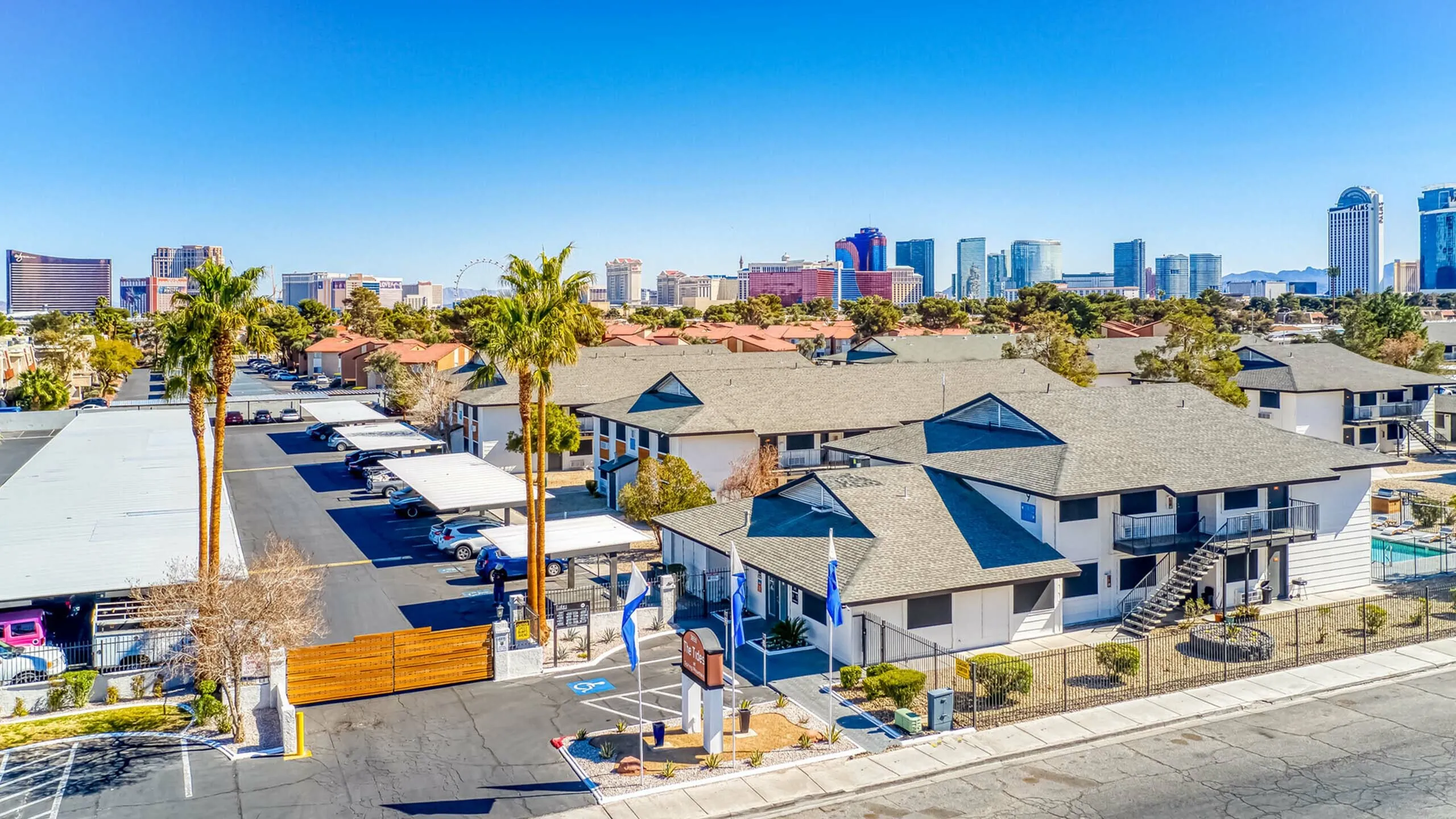 Vibrant suburban apartment community with palm trees, city skyline backdrop, and modern amenities.