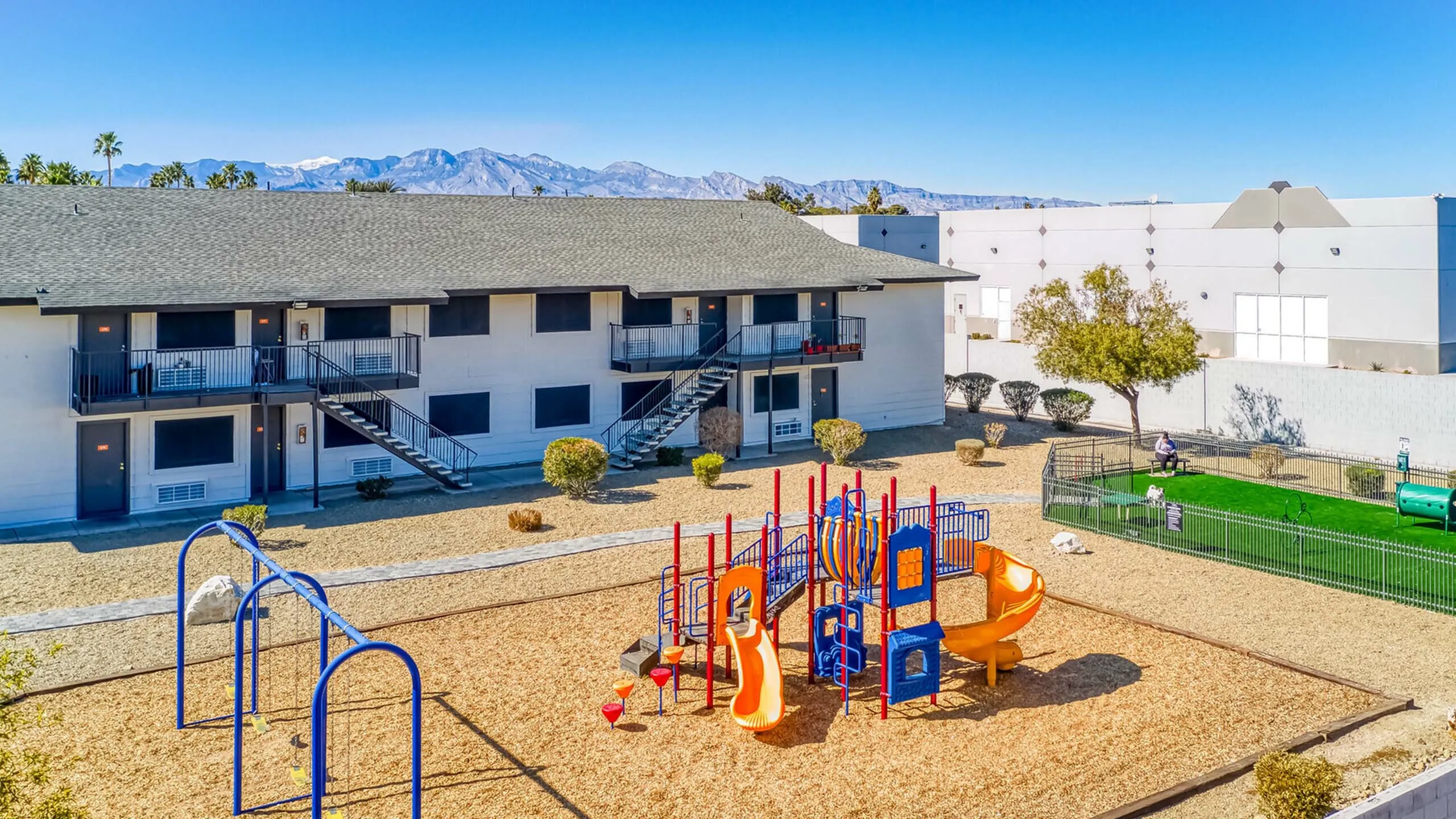 Charming apartment complex with scenic mountain views, featuring a vibrant playground and inviting outdoor spaces.