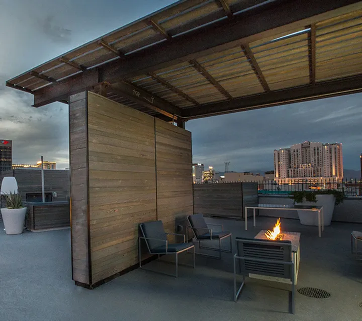 Chic rooftop terrace featuring modern seating and a cozy fire pit, offering stunning city skyline views.