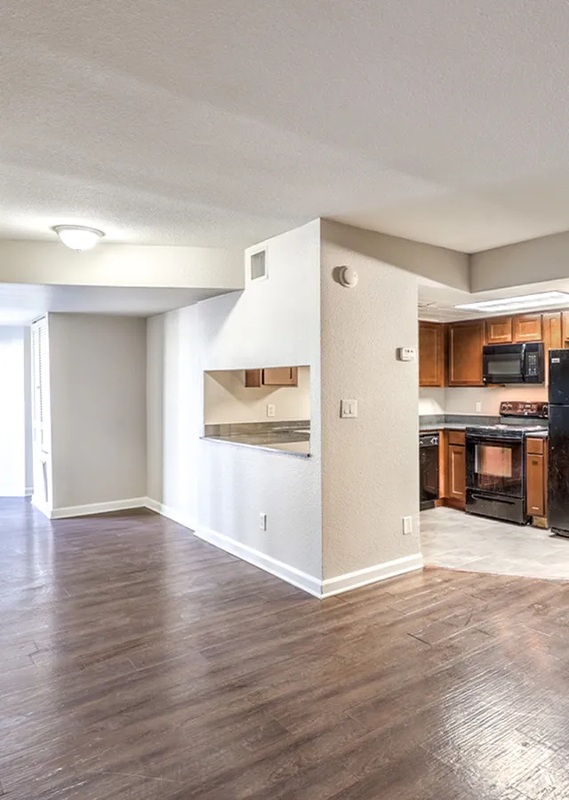 Bright open-concept living space with elegant hardwood floors and modern kitchen featuring dark wood cabinets.