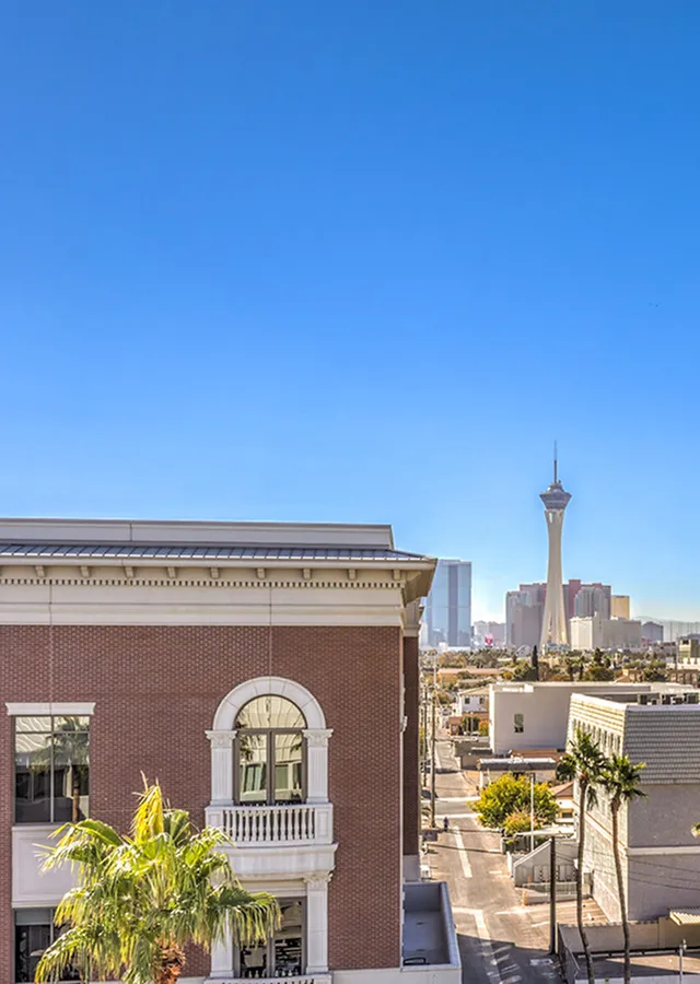 Charming urban view highlighting a classic brick building with the iconic city skyline in the background under a clear blue sky.