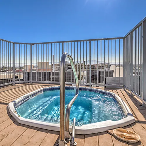 Inviting rooftop deck showcasing a shimmering hot tub with cityscape views under a bright blue sky.