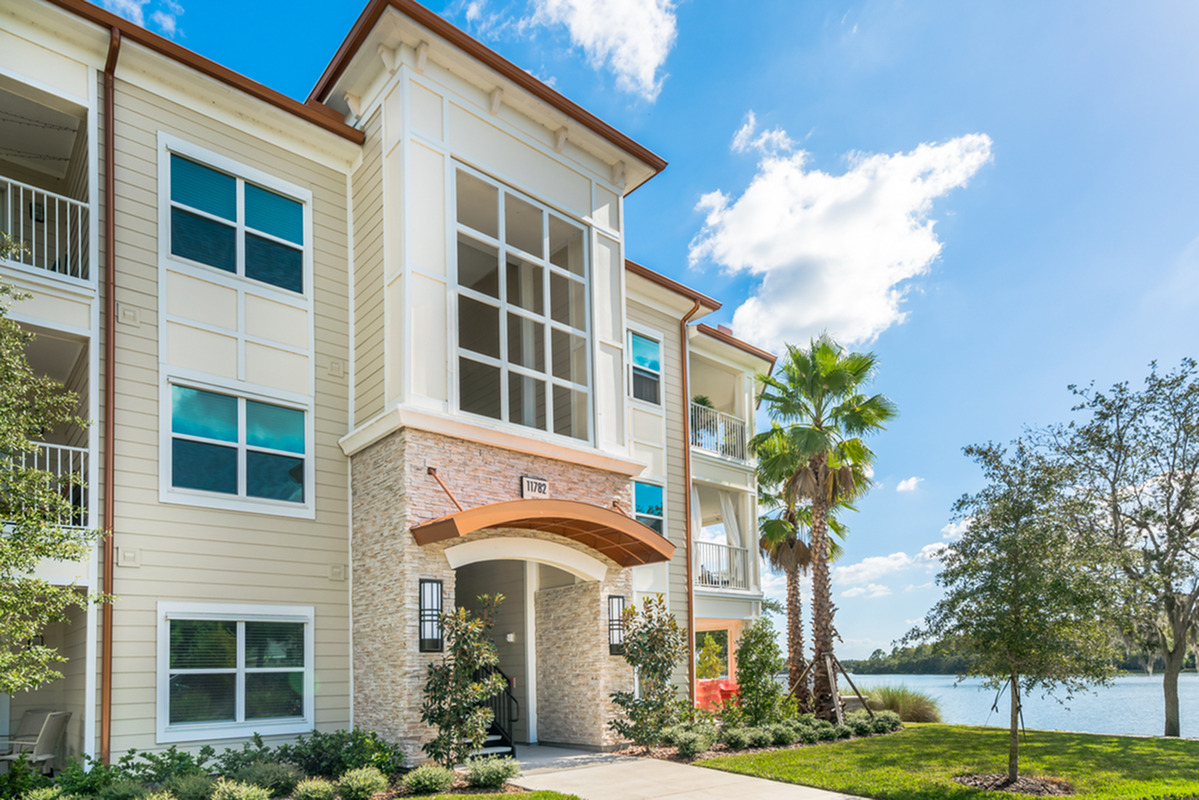 View of Building Exterior, Showing Private Patios and Balconies, Landscape, and Nearby Lake at The Marq Highland Park Apartments