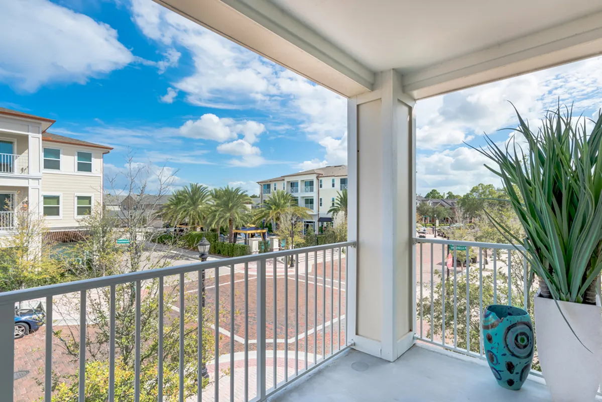 View of Balcony, Showing White Railing, Plants, View of Apartment Buildings, and Street at The Marq Highland Park Apartments