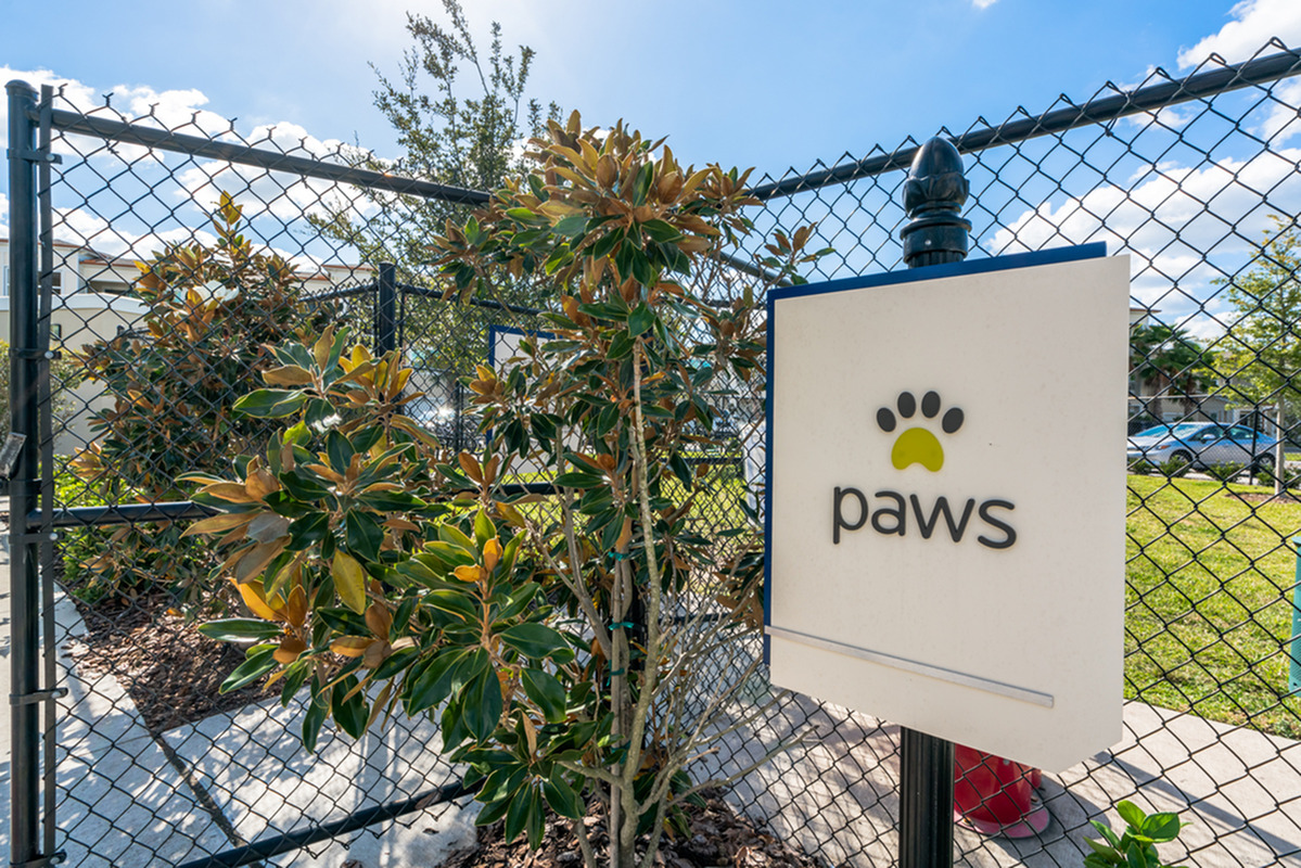 View of Dog Park, Showing Fenced-In Dog Park and Paws Signage at The Marq Highland Park Apartments in Westchase Tampa