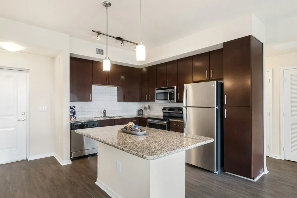 View of Cottonwood Lighthouse Point island kitchen showing wood cabinets, pendant lighting, and white subway tile backsplash