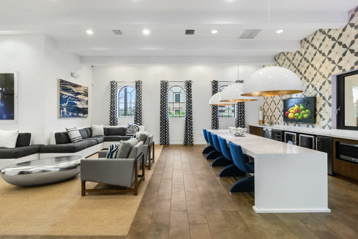 View of Cottonwood Lighthouse Point Clubroom Showin  Lounge-Style Seating, Large Pendant Lighting, Quartz Waterfall Countertops, and High Ceilings and Plank-Style Flooring