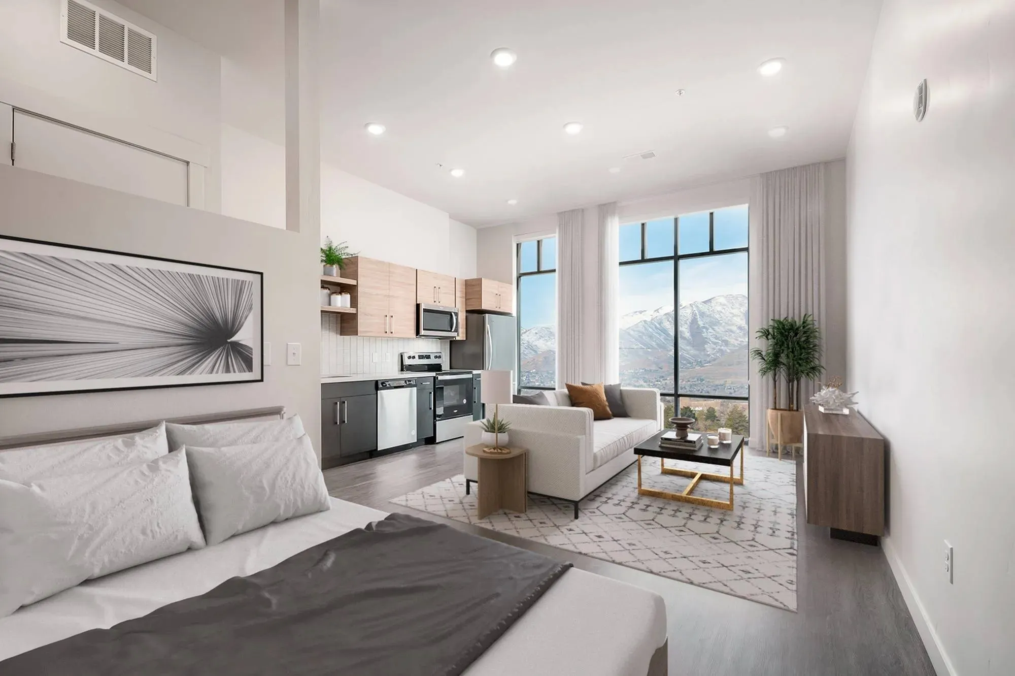 View of Park Avenue's Studio Apts in Salt Lake City Showing Mountain Views, Couch, Dining Room Table, Stainless Steel Kitchen Appliances, Bed, and Wood Cabinetry