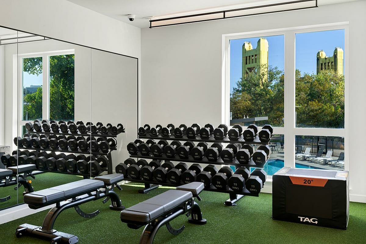 Bright and modern gym with extensive dumbbells and a view of the pool at 805 Riverfront in Sacramento with City View