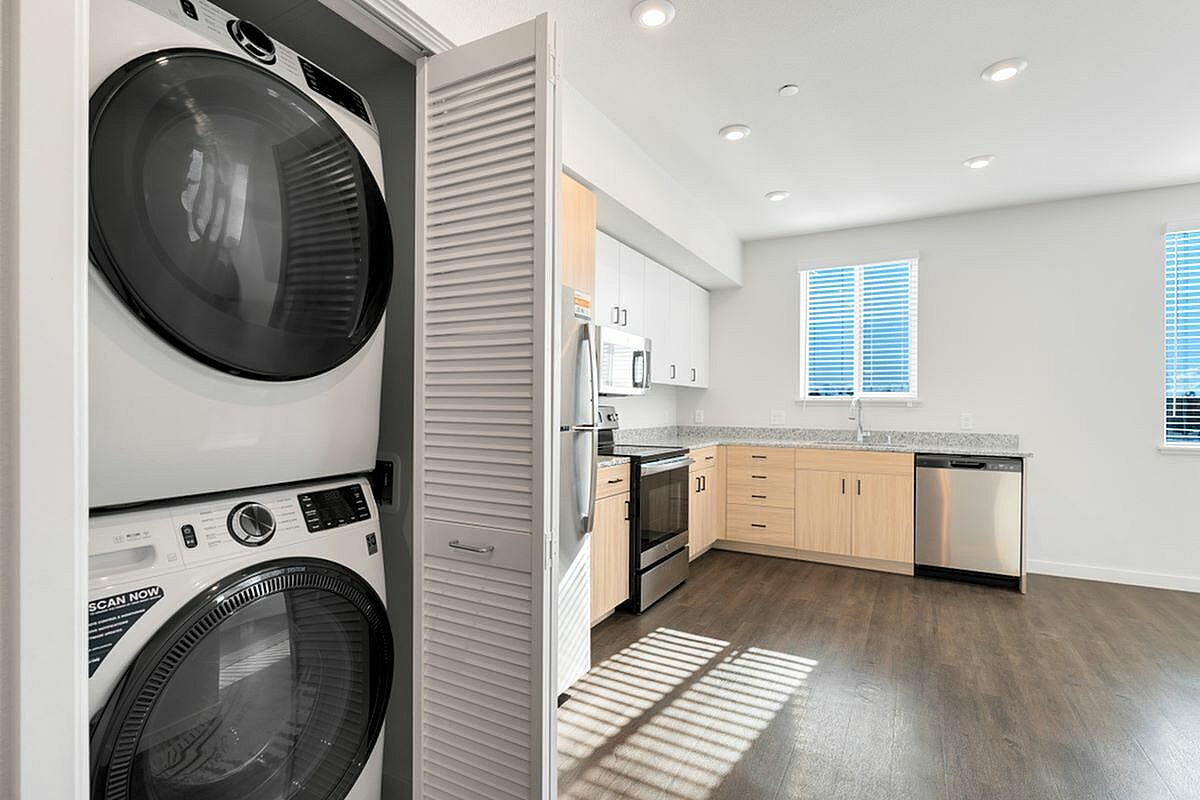 Modern kitchen with stainless steel appliances and an integrated washer-dryer in a sleek apartment.