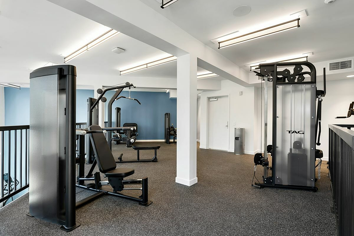 Modern apartment gym with weight machines and bright lighting at 805 Riverfront Apartments in Sacramento