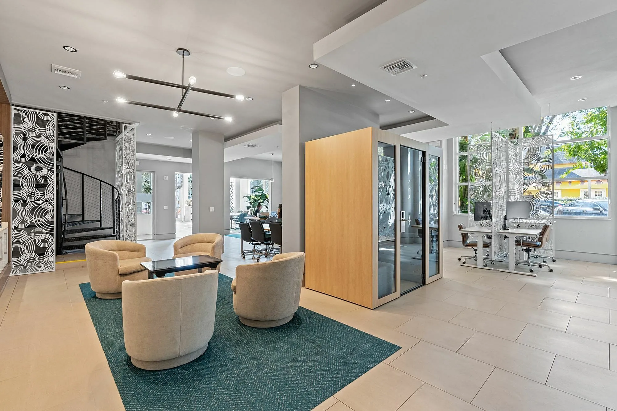 Spacious modern office lobby with stylish seating, spiral staircase, and glass-walled meeting room.