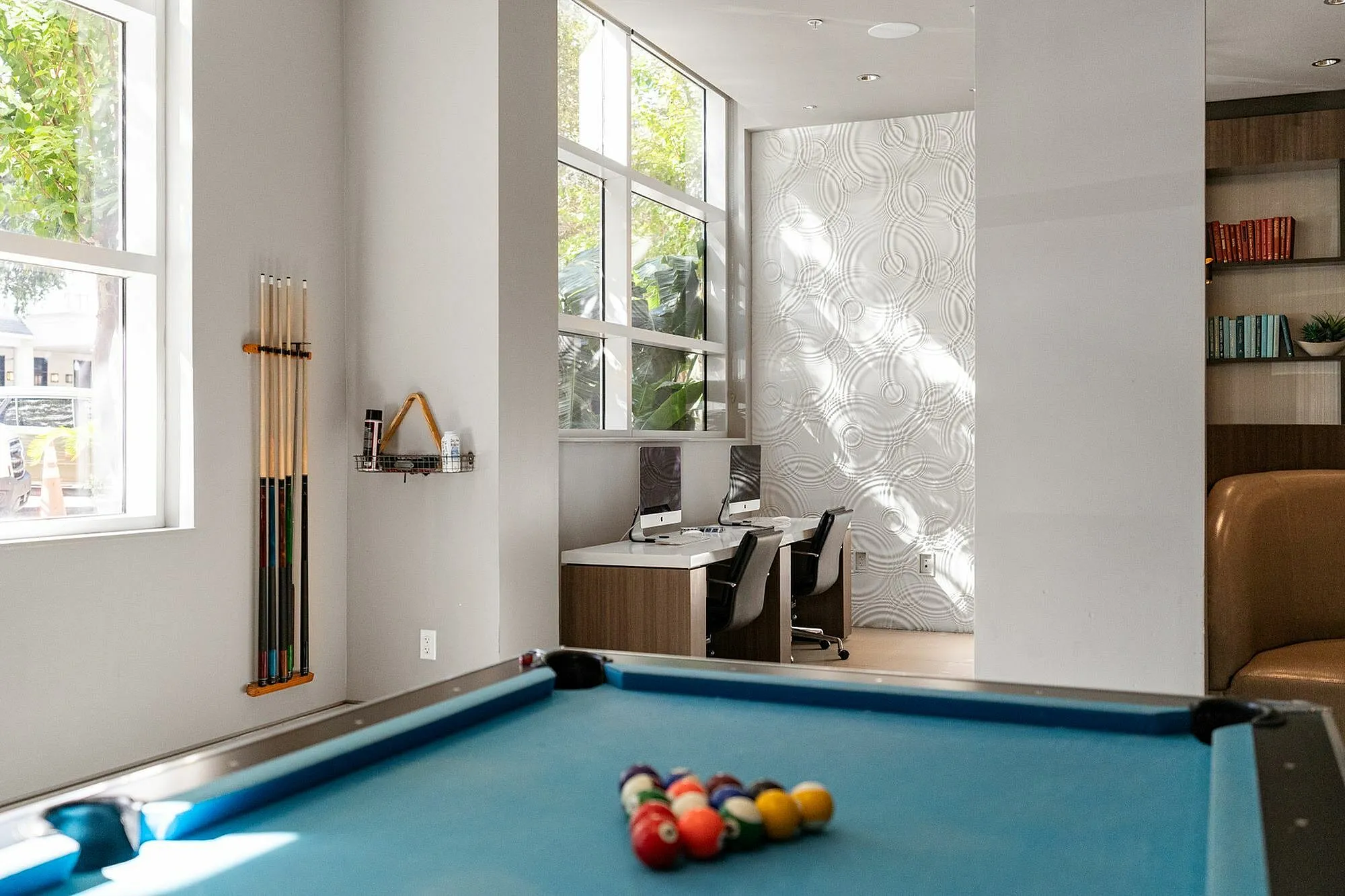 Bright and modern recreational space with a pool table and workstations.