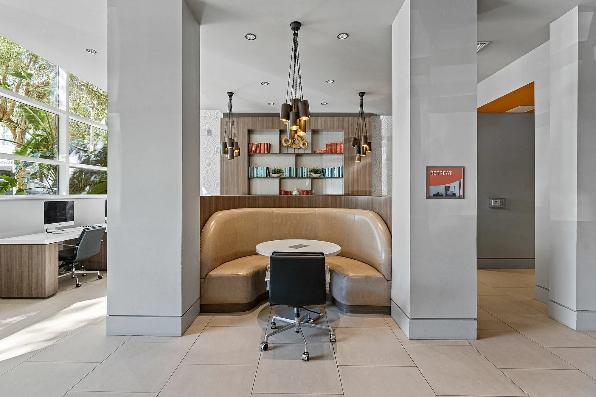 Sophisticated workspace featuring a cozy booth seating area and sleek computer desks.