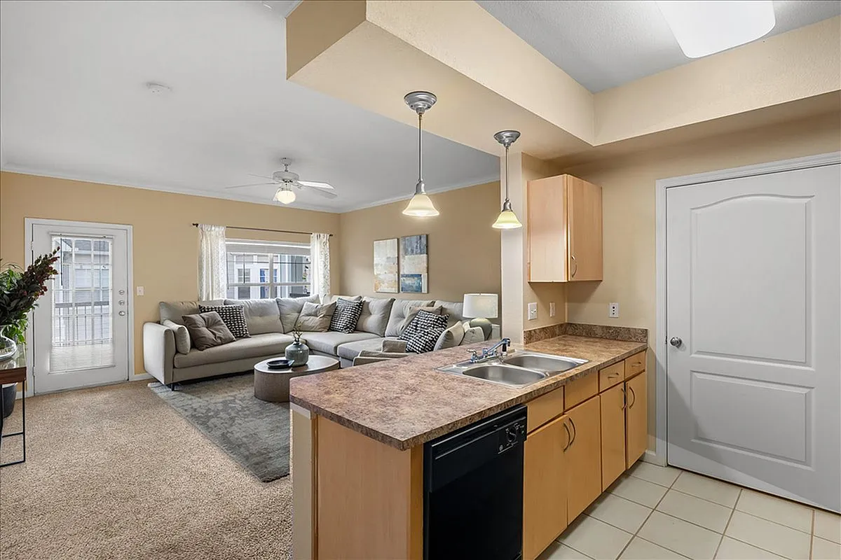 Bright modern living room with a cozy sectional sofa, open kitchen countertop, and stylish décor.