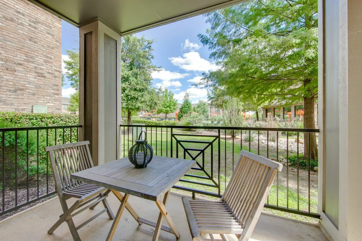 Charming balcony with wooden furniture overlooking lush greenery, ideal for relaxation and outdoor dining at Enclave on Golden Triangle.