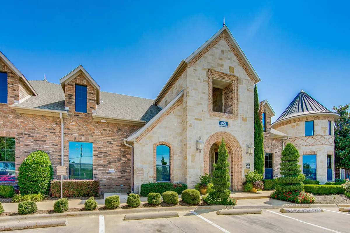 Charming stone and brick leasing office with elegant landscaping and a unique turret design at Enclave on Golden Triangle Apartments.