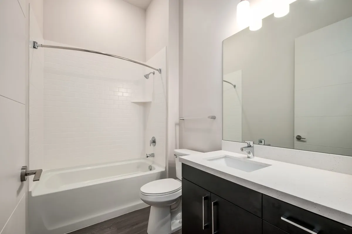 Modern bathroom with sleek vanity, large mirror, and pristine bathtub in a contemporary apartment.