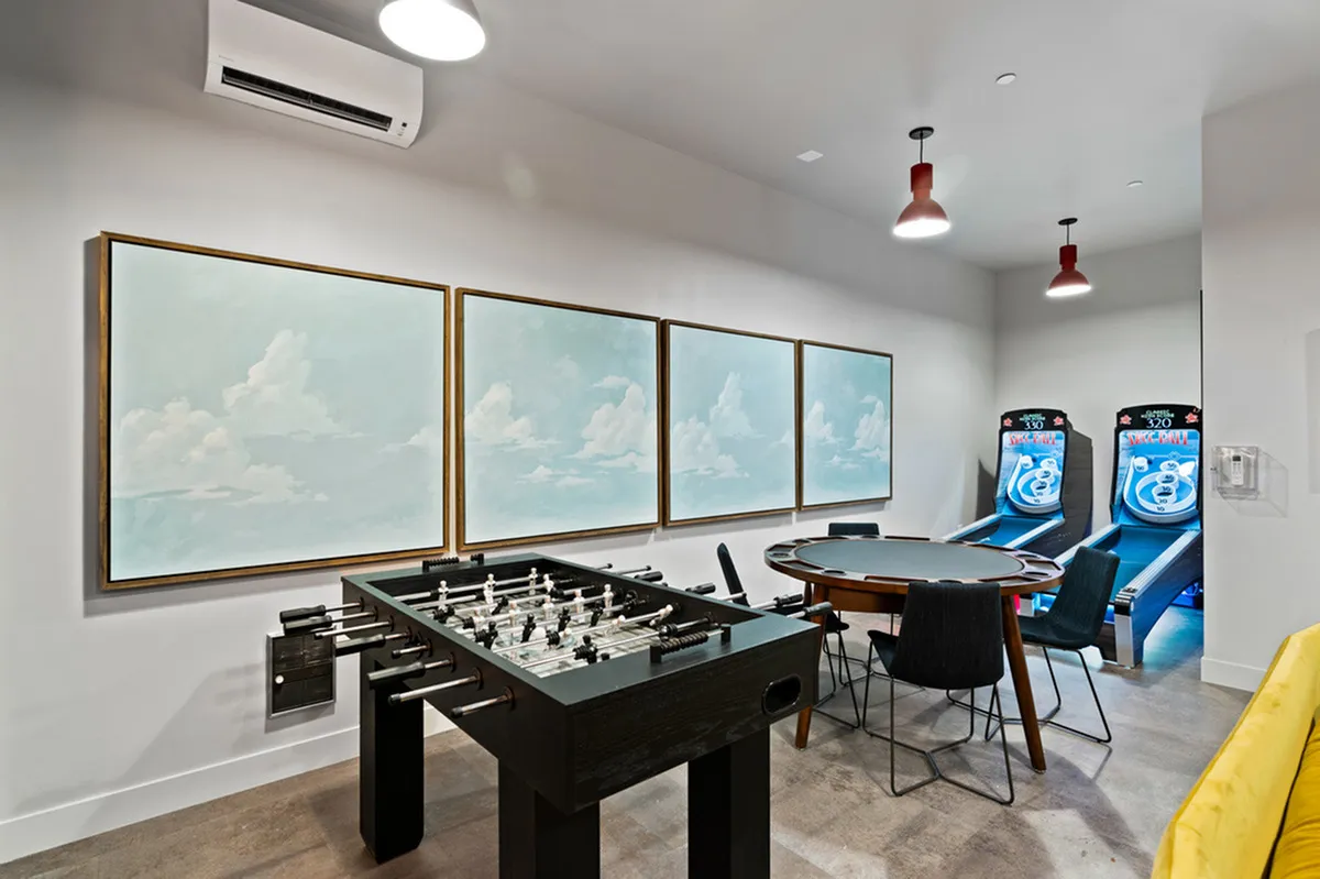 Chic game room featuring a foosball table, poker table, and exciting skee-ball machines under modern lighting.