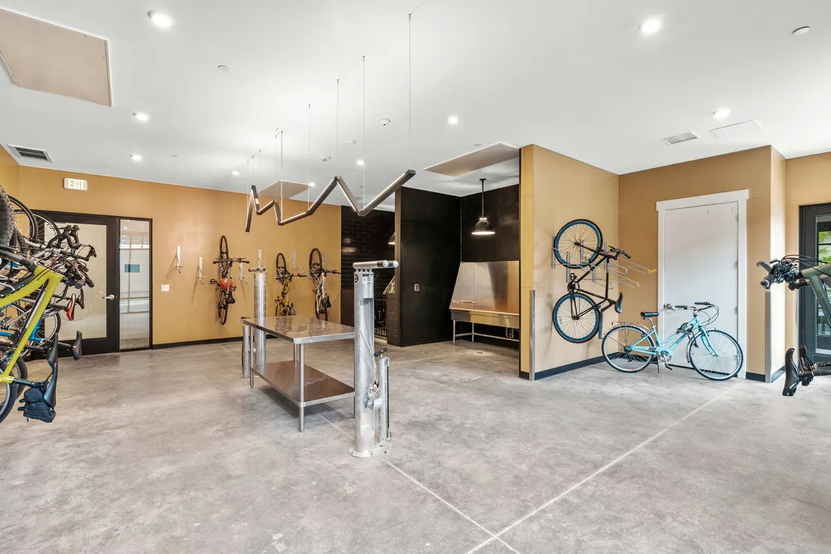 Modern bicycle storage room with wall-mounted racks, spacious repair station, and sleek lighting.